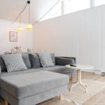 Ein Wohnzimmer mit grauem Sofa, weißer Couchtisch und Holzboden.