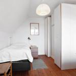 Bedroom with bed, wardrobe, and desk on wooden floor.