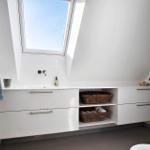 Bathroom with sloped ceiling, window, sink, and bath accessories.