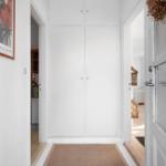Hallway with white cabinets, rug, and picture on the wall.