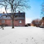 Red brick house with snow-covered roof and bare trees in the yard.
