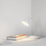 Lamp on nightstand beside bed with book.