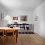 Dining room with wooden table, chairs, and bookshelf on the wall.