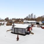 Snow-covered garden with red house and glass conservatory.