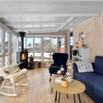Living room with fireplace, sofa and armchair. Wooden walls and large windows.