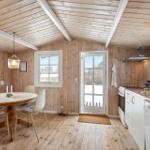 Kitchen and dining area with wooden walls, table, chairs, and windows.