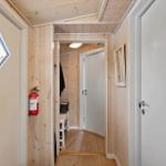 Hallway with wooden walls, fire extinguisher, and door to a room.