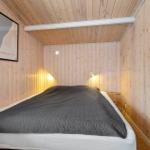 Bedroom with wooden walls and bed with dark quilt.