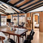Living and dining area with wooden floor and walls. View into bedroom.