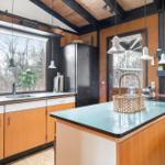 Kitchen with wooden walls, kitchen island, and view of outdoor area.