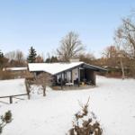 Snow-covered garden with modern house and terrace.