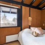 Bedroom with wooden walls, window, and bed with pillows.