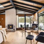 Living room with fireplace, wooden floor, and large window view of the garden.