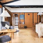 Living and dining area with wooden floor, sofa, chairs, and table.