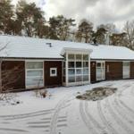 House with snow-covered roof and wooden facade in the forest