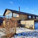 Modern house with snow-covered grounds and wooden fence