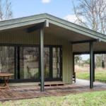 Moderne Hütte mit Holzterrasse und großem Fenster. Grün-dach und freier Blick in die Natur.