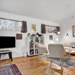 Wohnzimmer mit Sofa, Stühlen, Fernseher und Holzboden.