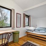 Schlafzimmer mit Bett, Schreibtisch und Fenster mit Blick auf Wald.