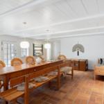 Großer Raum mit Holztisch, Bänken und rustikalem Bodenbelag.