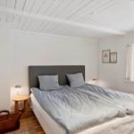 Schlafzimmer mit Bett, Fenster und Nachttisch.