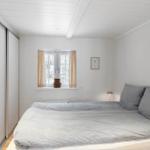 Schlafzimmer mit Bett, Fenster und Schiebetüren.