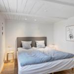 Schlafzimmer mit Bett, Fenster und Wandbild.