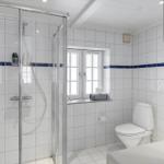 Badezimmer mit Dusche, Toilette und Fenster.