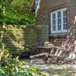 Hinterhof mit Holzstühlen, Tisch und Blumen vor Backsteinhaus