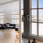 Wohnraum mit schwarzer Couch und Holzboden. Blick durch Fenster auf schneebedecktes Feld.