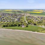 Aeriale Aufnahme einer Küstenlandschaft mit Häusern, Feldern und Meer.