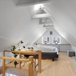 Schlafzimmer mit Dachschrägen, Holzboden und Arbeitsplatz mit Tisch und Stuhl.