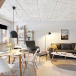 Wohn- und Essbereich mit Sofa, Tisch und Stühlen. Holzboden und heller Raum.