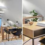 Schreibtisch mit Lampe und Buch in einem Dachzimmer mit Holzboden und Fenster.