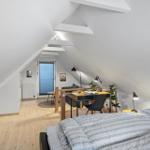 Schlafzimmer mit Doppelbett, Schreibtisch und Schlafbereich unter Dachschräge.