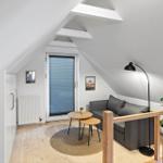 Dachgeschosswohnung mit Sofa, Tisch, Lampe und Pflanze.