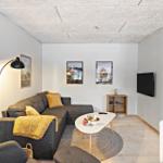 Wohnzimmer mit Sofa, Tisch und Fernseher an der Wand.