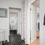 Hallway with doors to bathroom and bedroom, black tiles, mirror, and clothing on the wall.