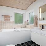 Bathroom with bathtub, sink, and wooden ceiling.