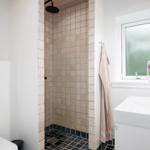 Bathroom with shower, sink, and toilet. Window with flower vase.