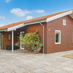 Wooden house with terrace, grill, and flower bed. Number 45. Stone paving in front of the house.