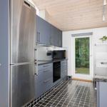 Kitchen with gray cabinets, stainless steel refrigerator, and black sink.