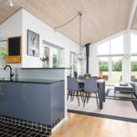 Kitchen with dining area and living room with wooden ceiling and large windows.