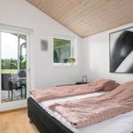 Bedroom with bed, door to balcony, and window. Wooden ceiling and wall art.