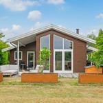 Modern wooden cabin with large windows and terrace with garden furniture.
