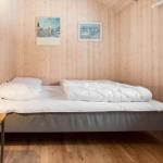 Bedroom with bed, nightstand, and window. Wooden walls and floor.
