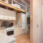 Kitchen with wooden walls, stainless steel sink, and refrigerator. View into bathroom with towel.