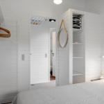 Schlafzimmer mit weißem Holz, Bett, Kleiderschrank und Spiegel.