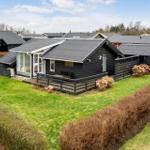 Schwarzes Holzhaus mit Terrasse und grünem Garten. Modernes Design mit Glasfront.