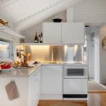 Küche mit weißen Schränken, Edelstahlspüle und Kühlschrank an der Wand.